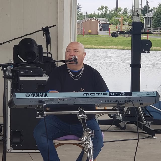 Jim singing and playing keyboard at an outdoor show